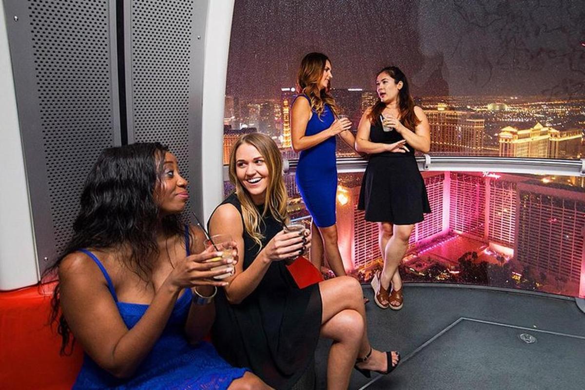 a group of women sitting on a ledge with wine glasses