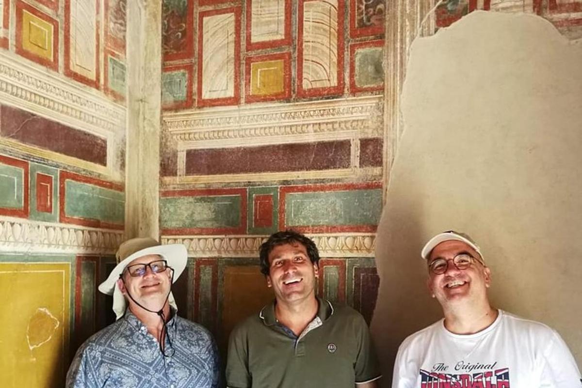 three men are standing in front of a wall