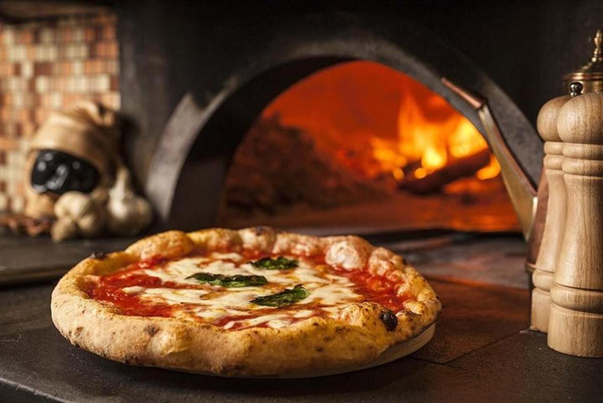Una pizza sentada frente a un horno de pizza.