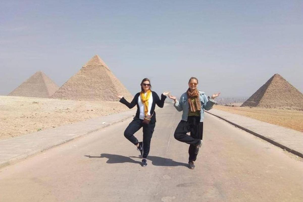 dva lidé běží po silnici před pyramidami