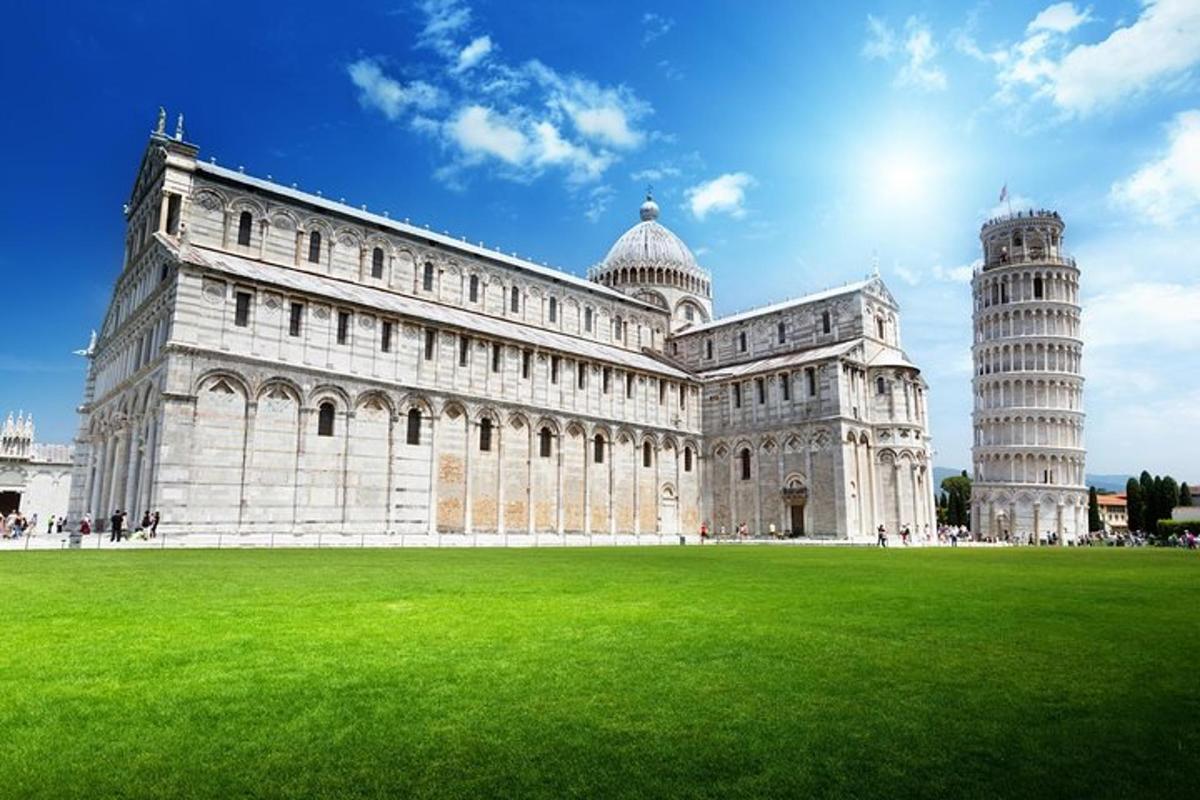 um grande edifício com uma torre inclinada e um campo verde