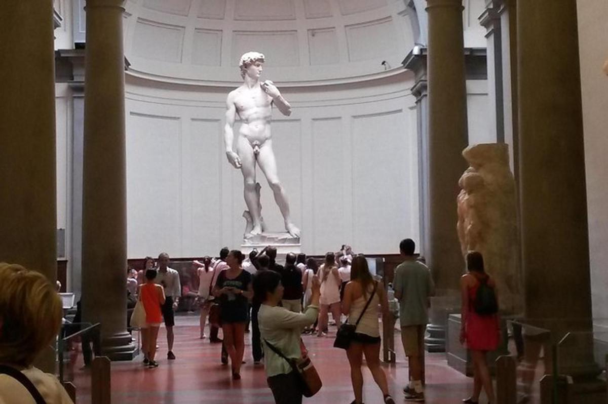 a crowd of people standing around a statue in a museum