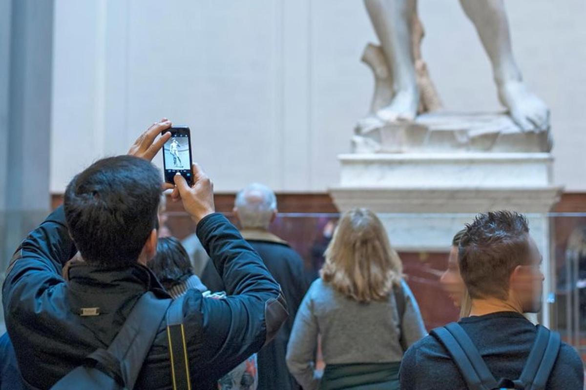 a man taking a picture of a statue with his cell phone