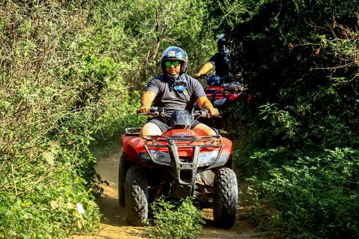 un uomo che guida un quad lungo un sentiero sterrato