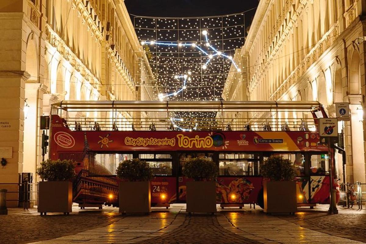 a red double decker bus parked in a street with lights