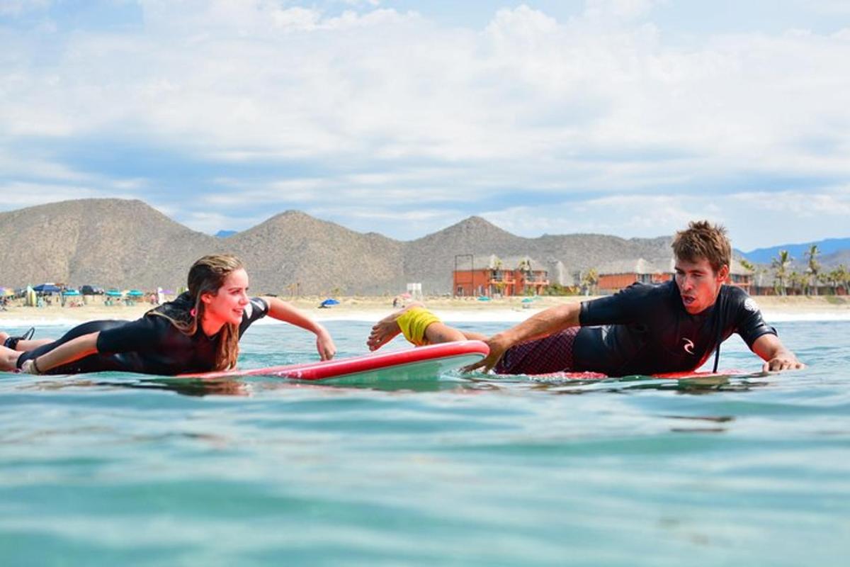 Dos personas tumbadas sobre tablas de surf en el agua