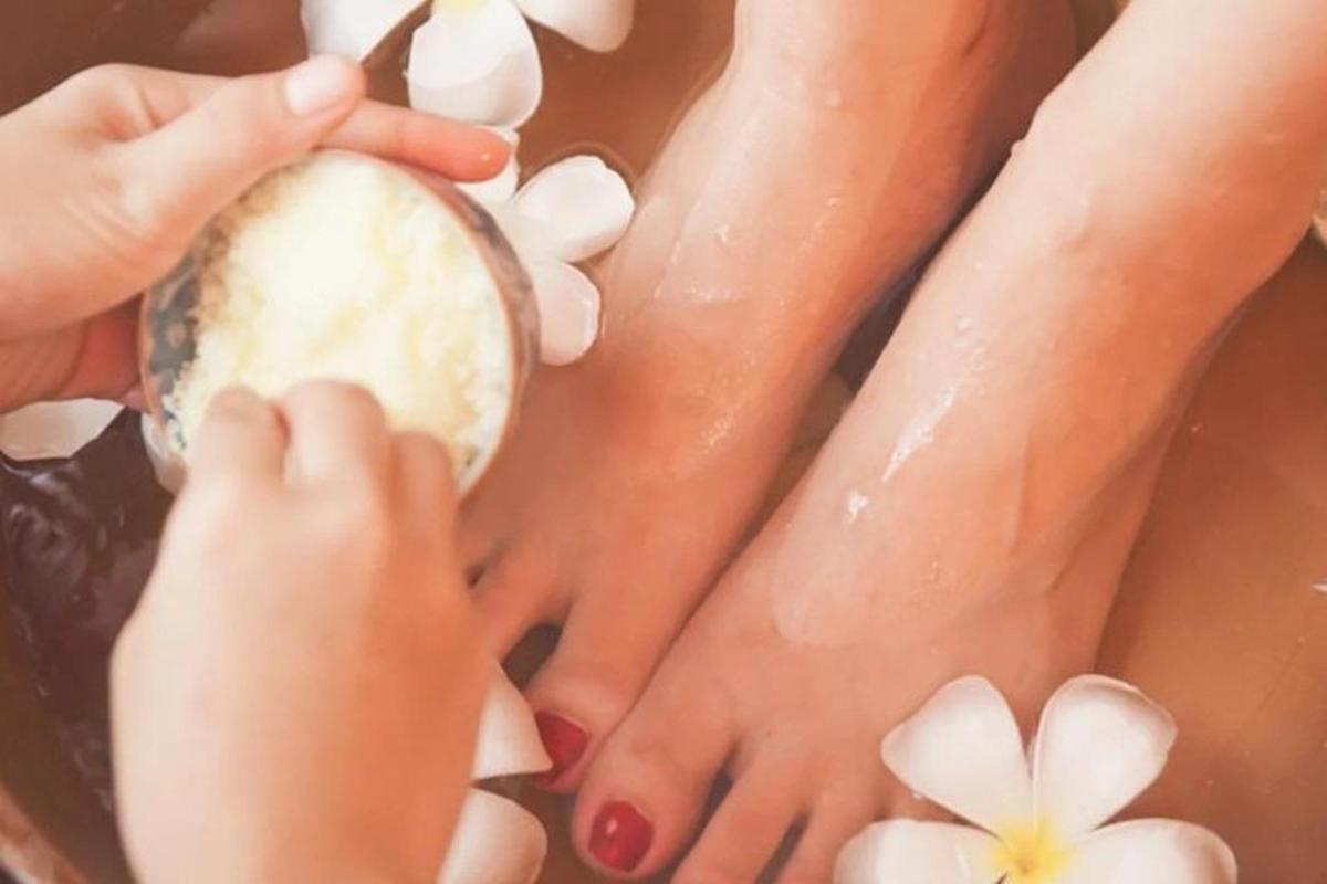 una dona s'està aplicant un bany de peus amb les mans i flors