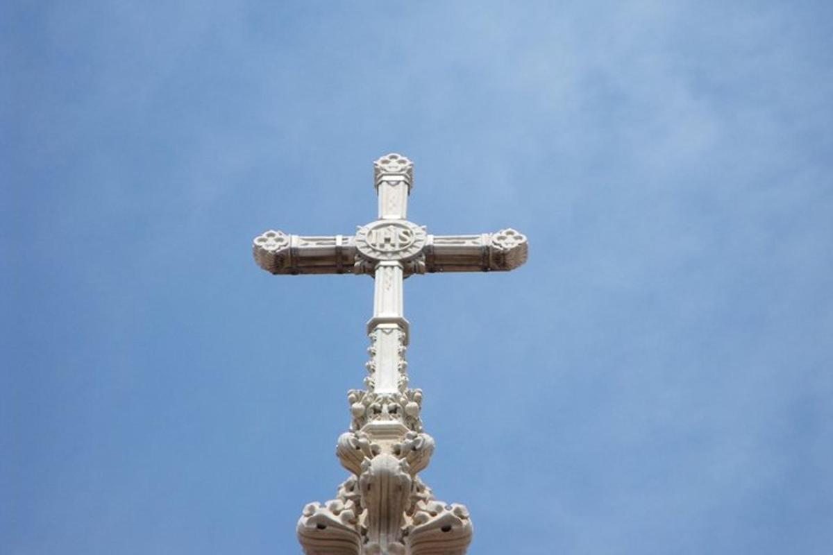 Una cruz de plata con un cielo azul al fondo