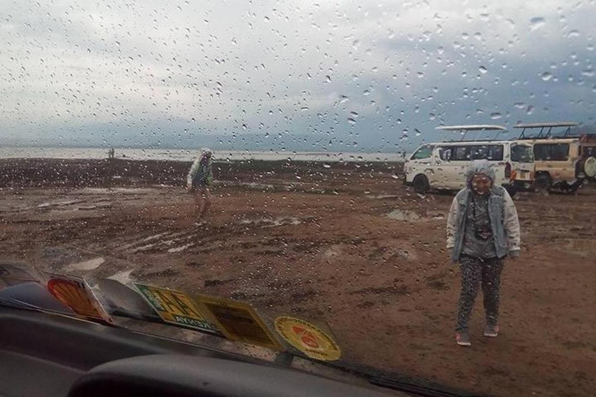 dua orang berdiri di pantai dalam hujan
