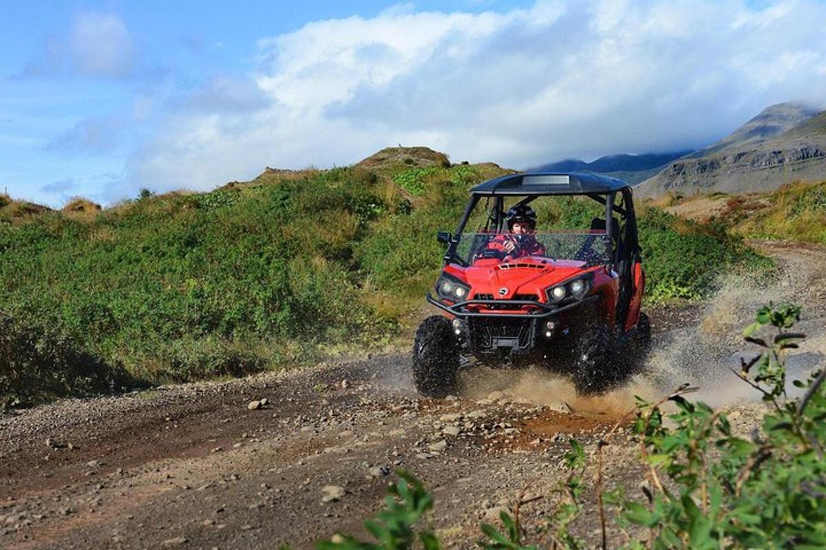 een persoon die op een rode ATV rijdt op een onverharde weg