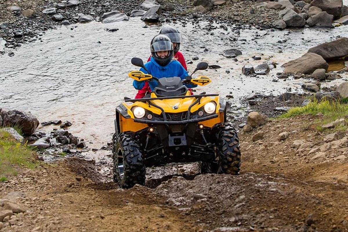 eine Person, die mit einem Quad durch einen Fluss fährt