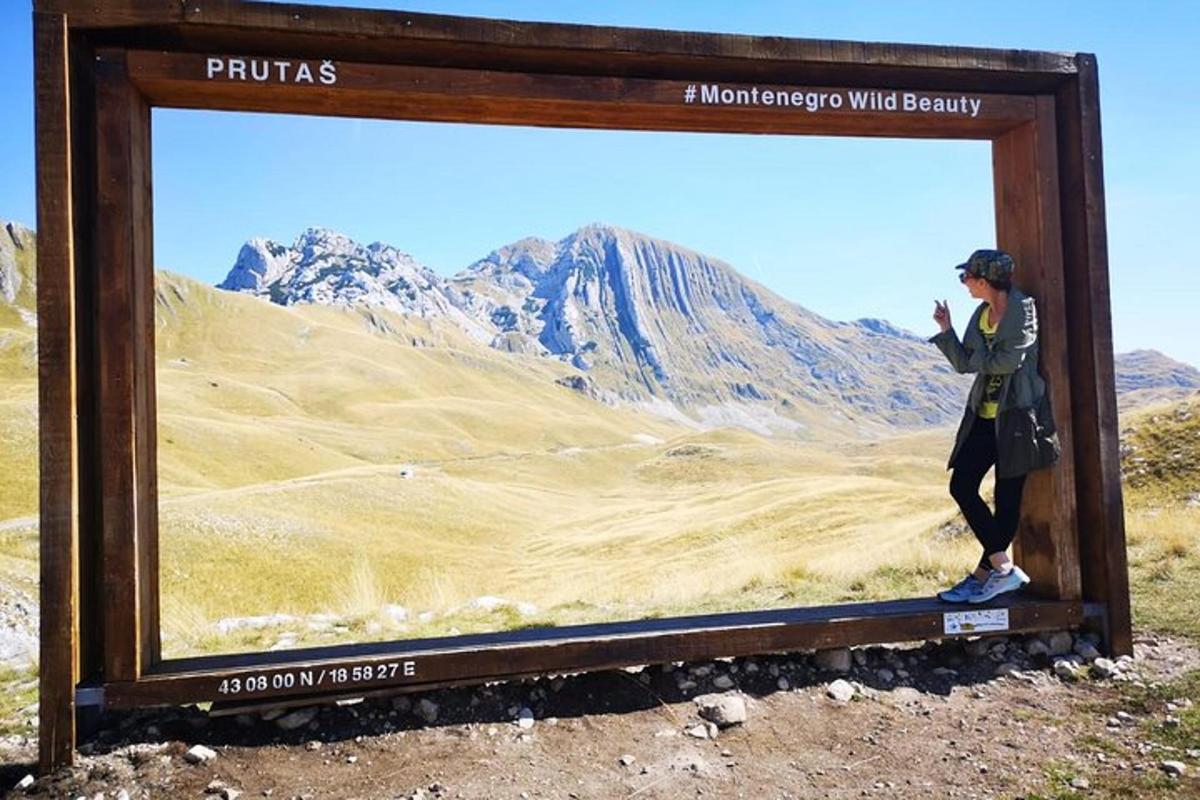 Una persona parada frente a un cartel en las montañas.