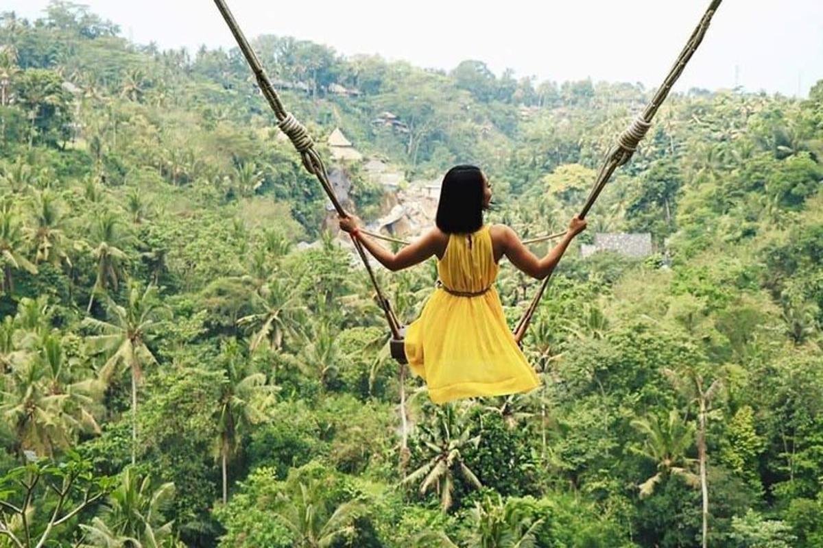 Una mujer con un vestido amarillo balanceándose en un puente de cuerda sobre un bosque.