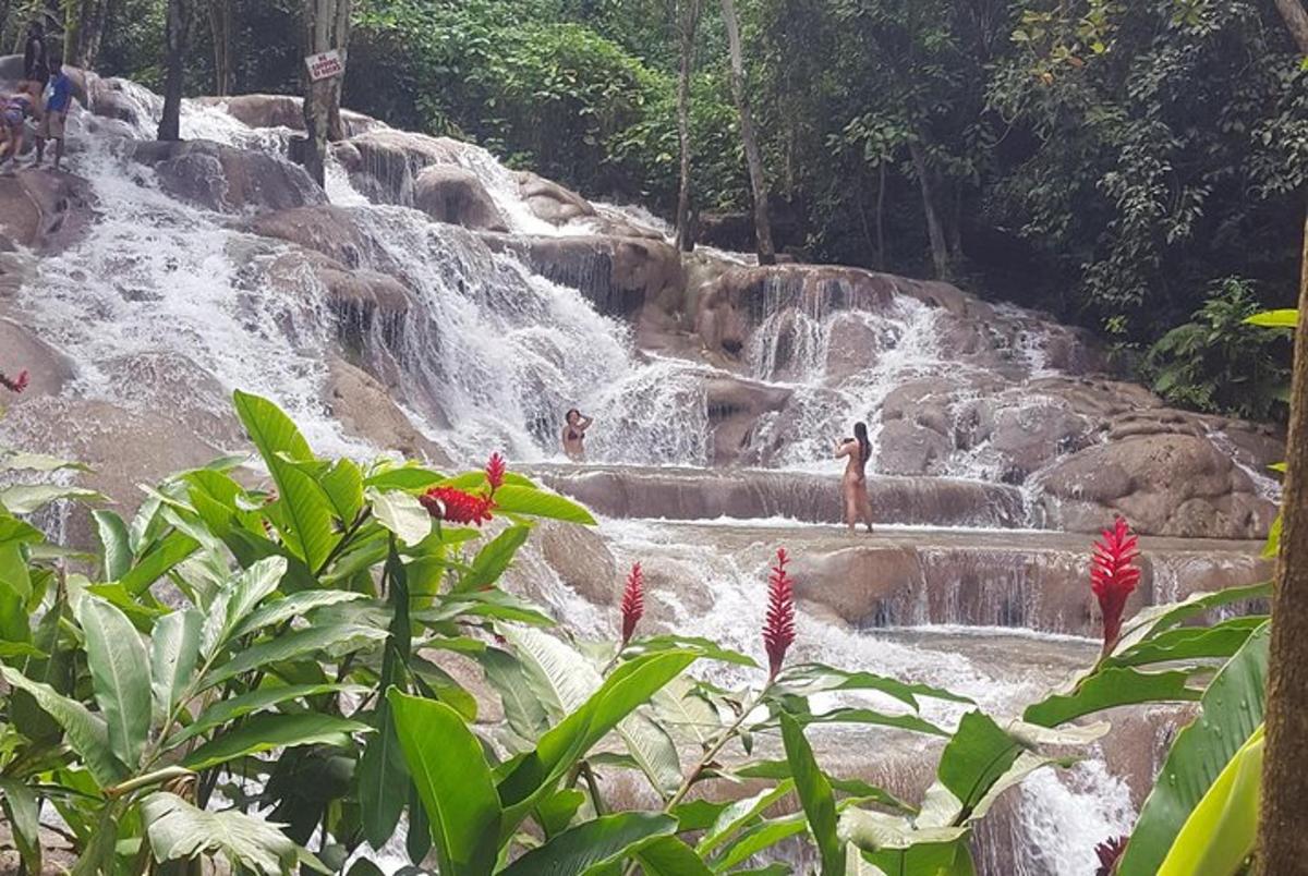 uma cachoeira com pessoas em pé nos degraus em frente a ela