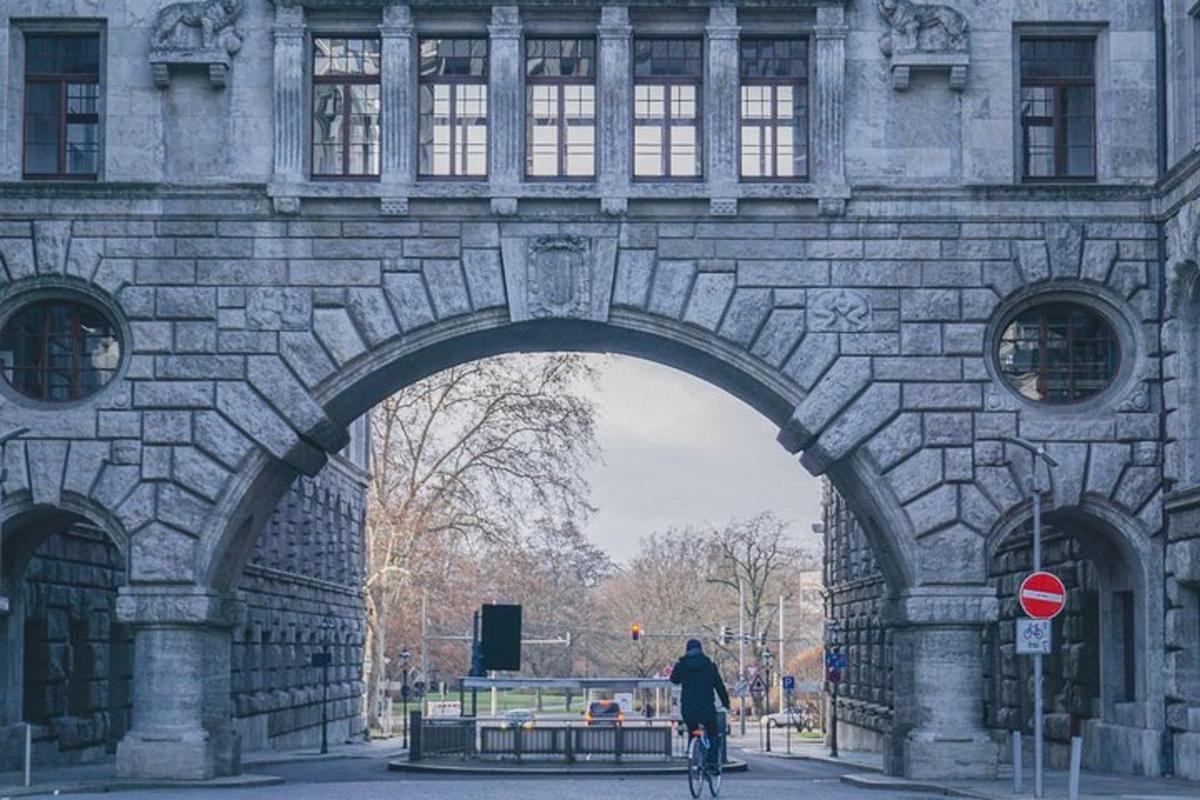 a person riding a bike under a stone bridge