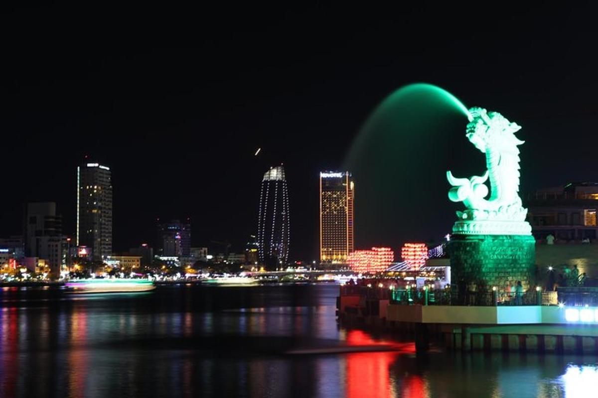 uma fonte verde em frente a uma cidade à noite