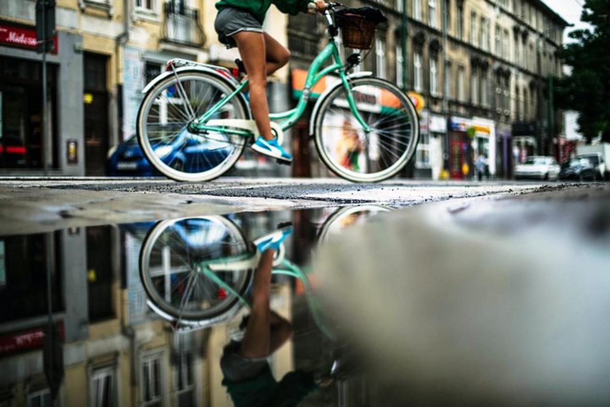 cilvēks brauc ar velosipēdu pa pilsētas ielu