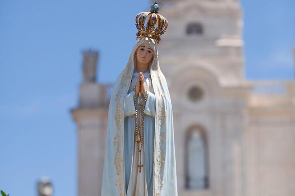 o figurină religioasă purtând o coroană deasupra unei clădiri