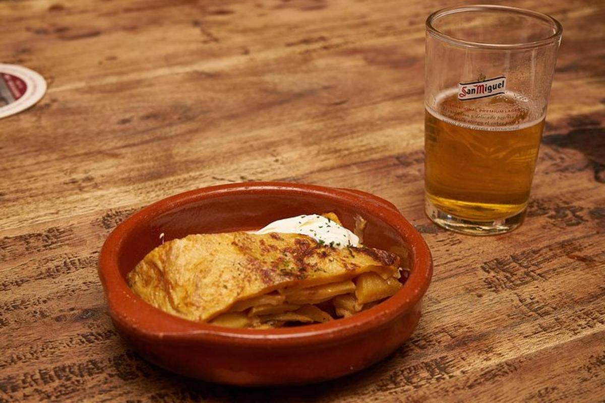 Un plato de comida y un vaso de cerveza sobre una mesa.
