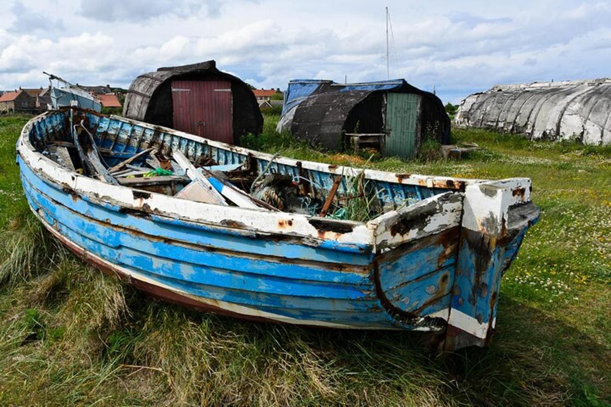 an old blue boat sitting in a field