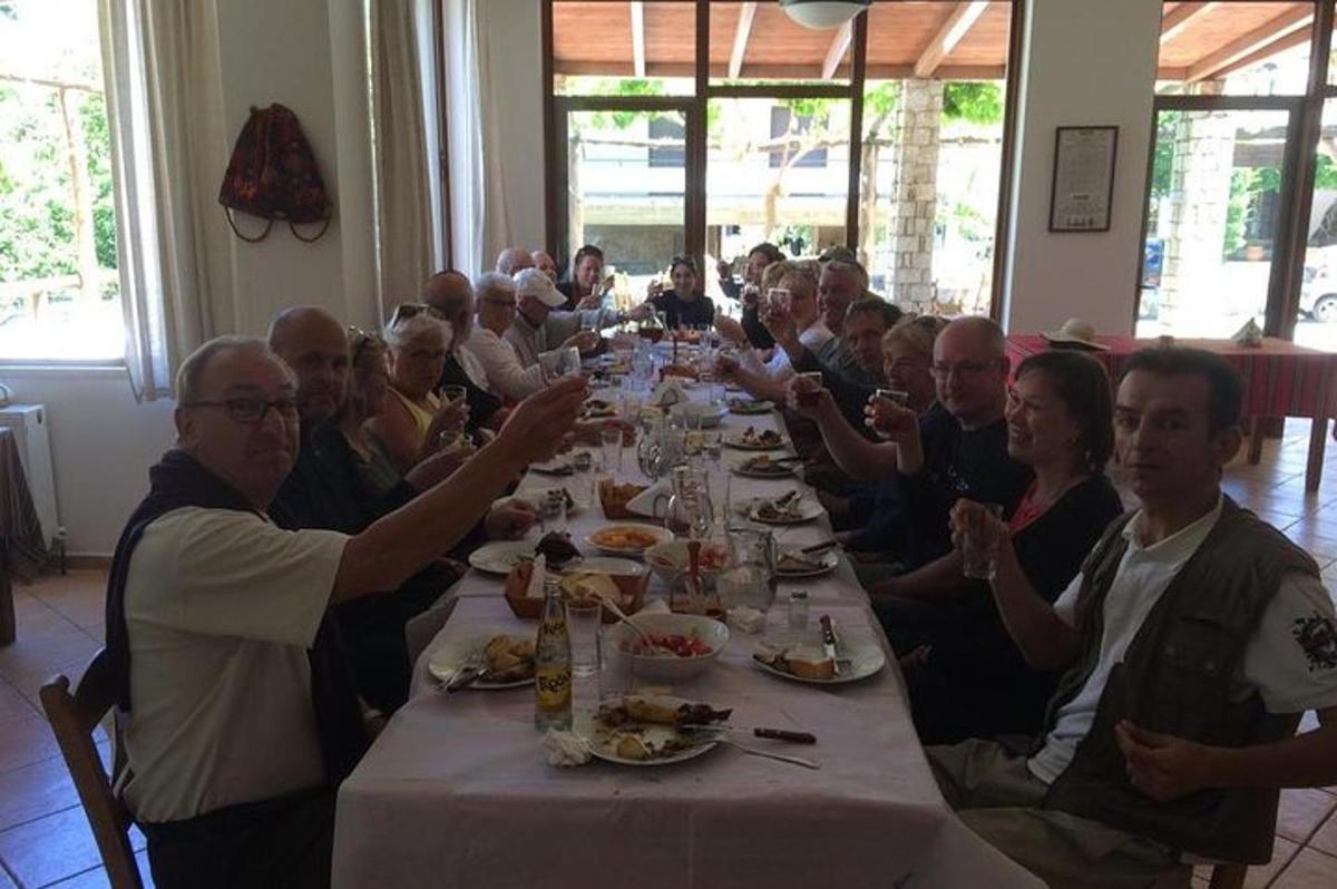 un grup de persones assegudes a una taula llarga menjant