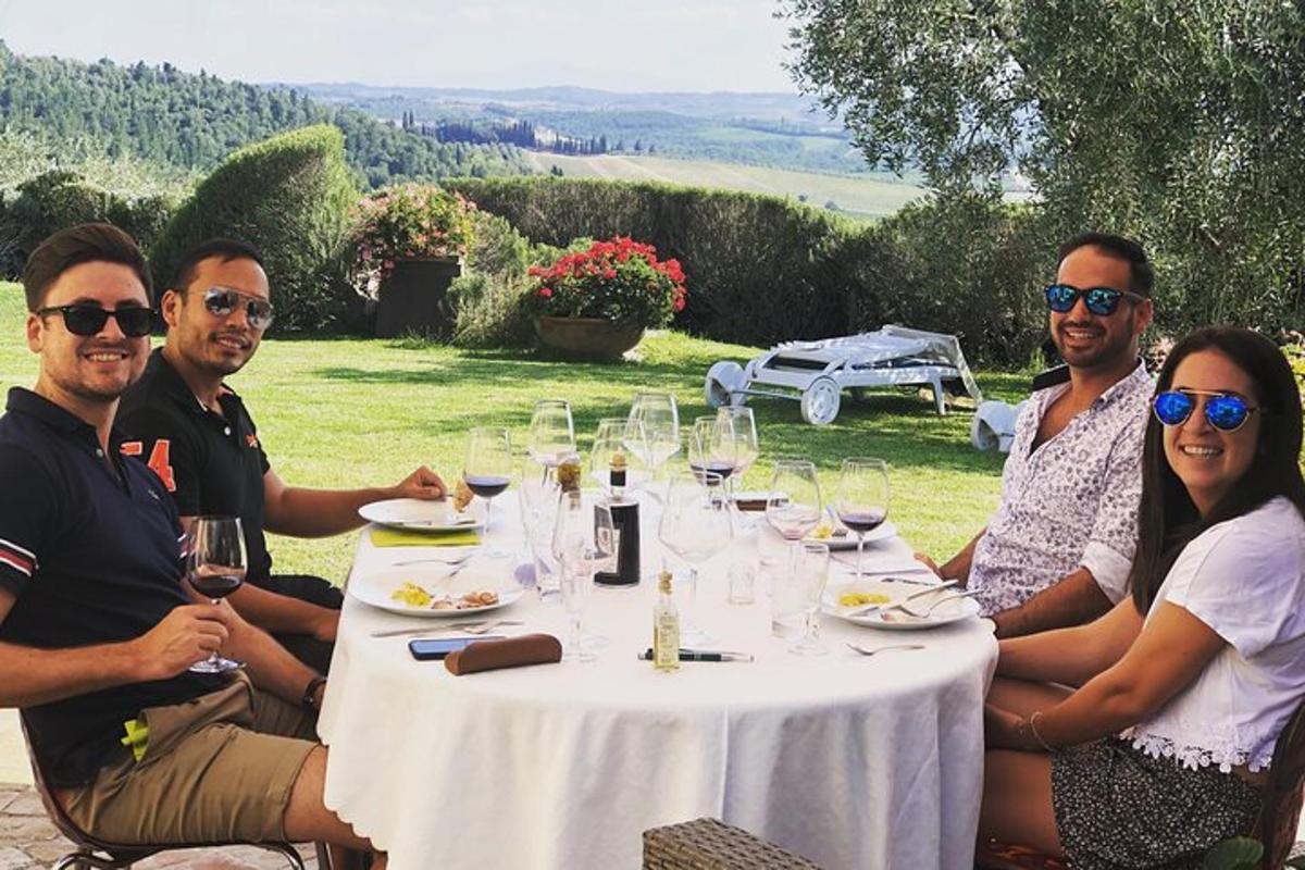 grupp inimesi istub laua ümber veiniklaasidega