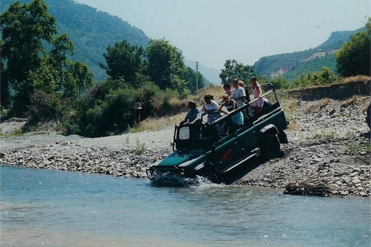 eine Gruppe von Menschen in einem Jeep, die einen Fluss überqueren