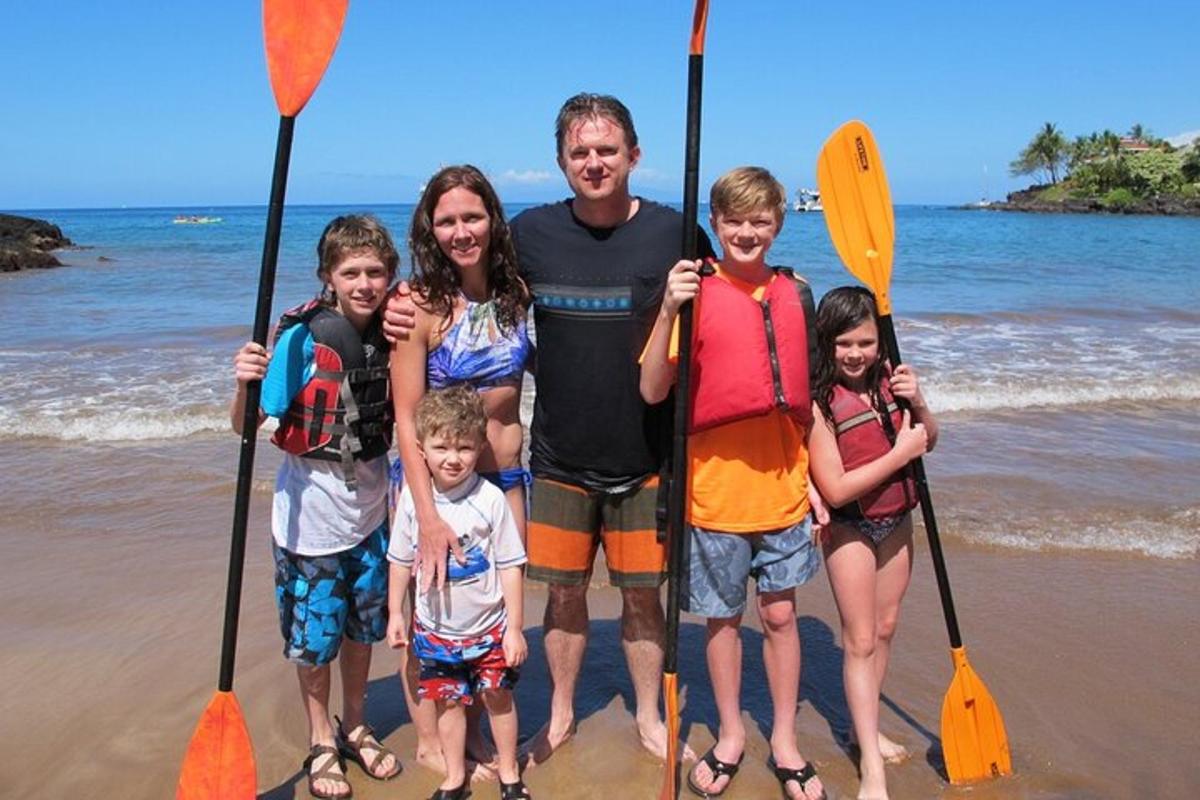 en mann og familien hans står på stranden med årer