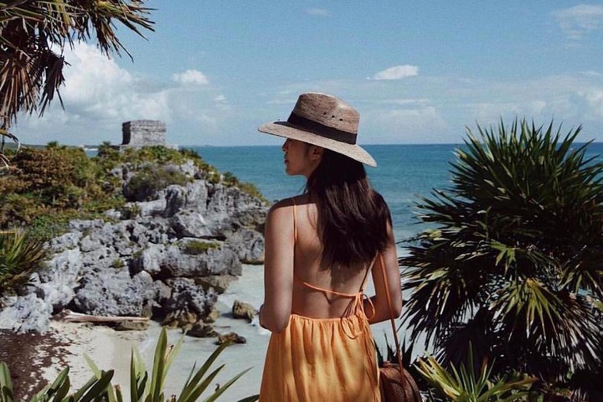 a woman in a hat is looking at the ocean
