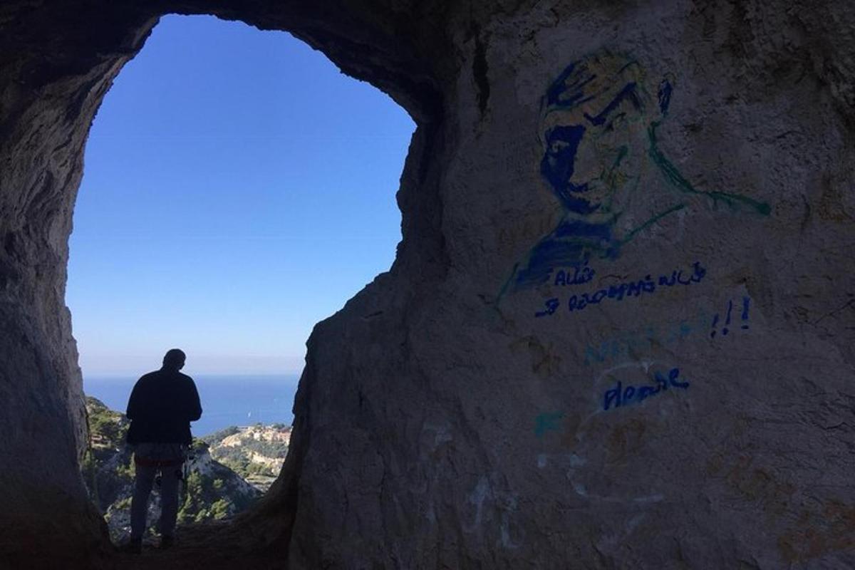 a man standing in a cave with graffiti on a rock