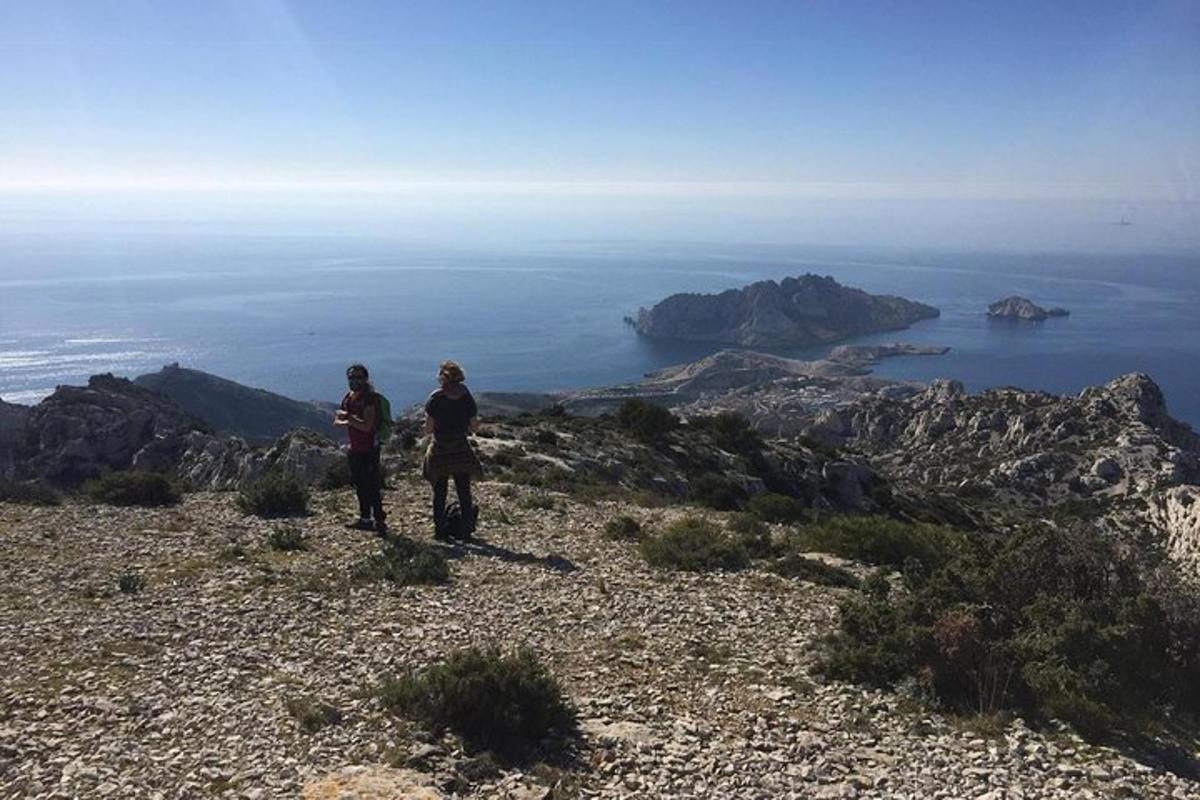 two people standing on a hill looking at the ocean