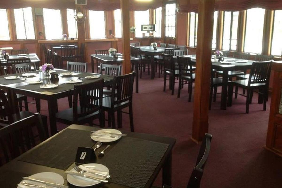 Un comedor con mesas y sillas y ventanas.