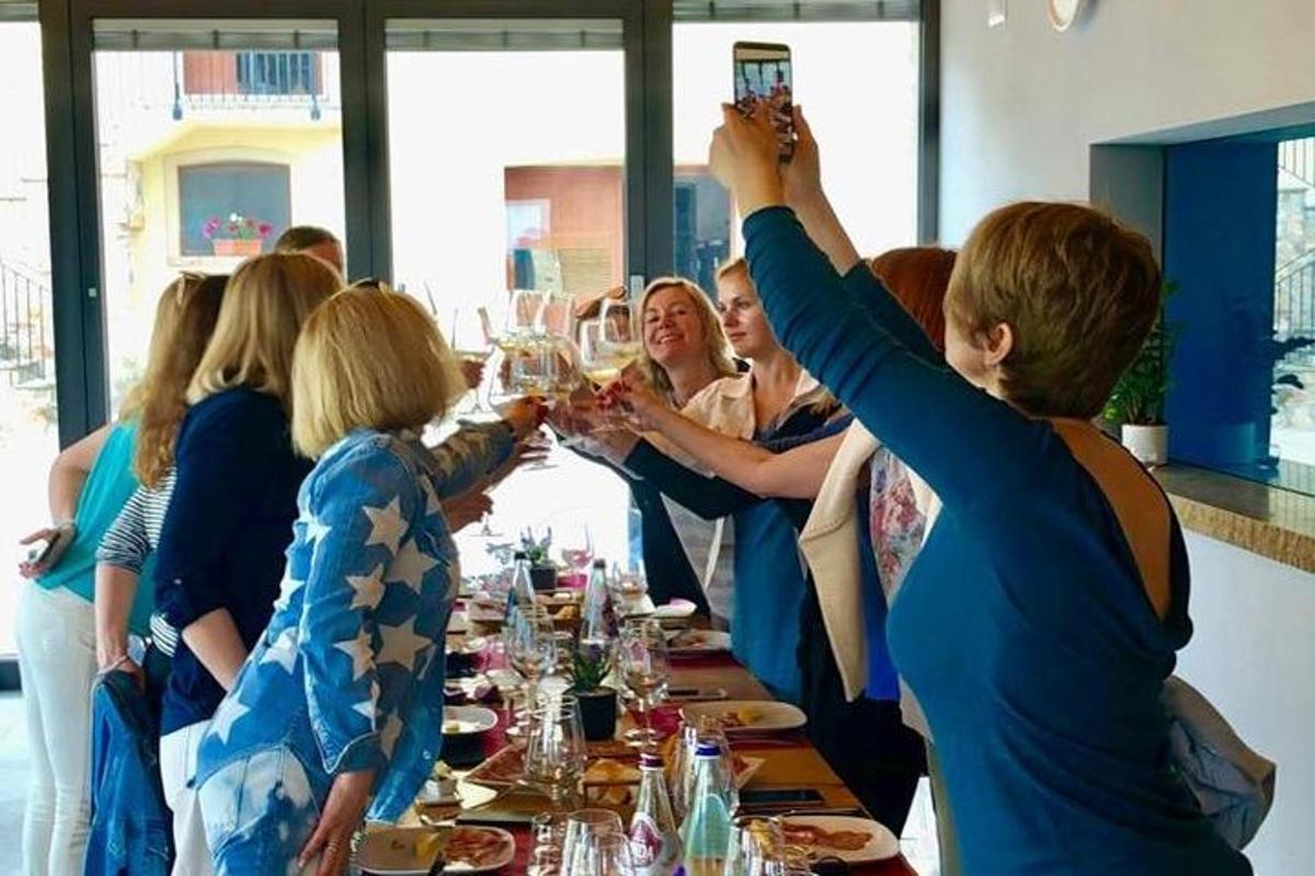 Un grupo de personas sentadas alrededor de una mesa bebiendo vino.
