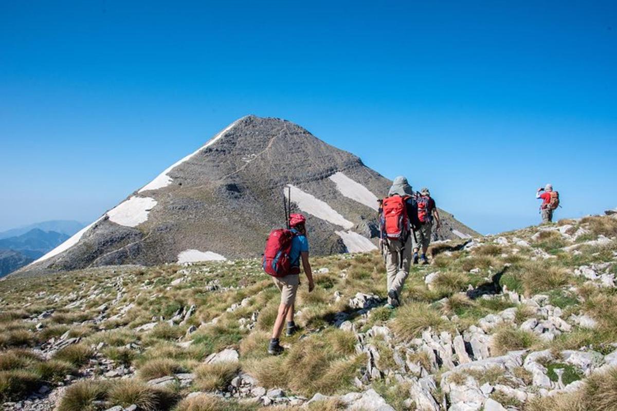drei Personen mit Rucksäcken wandern einen Berg hinauf