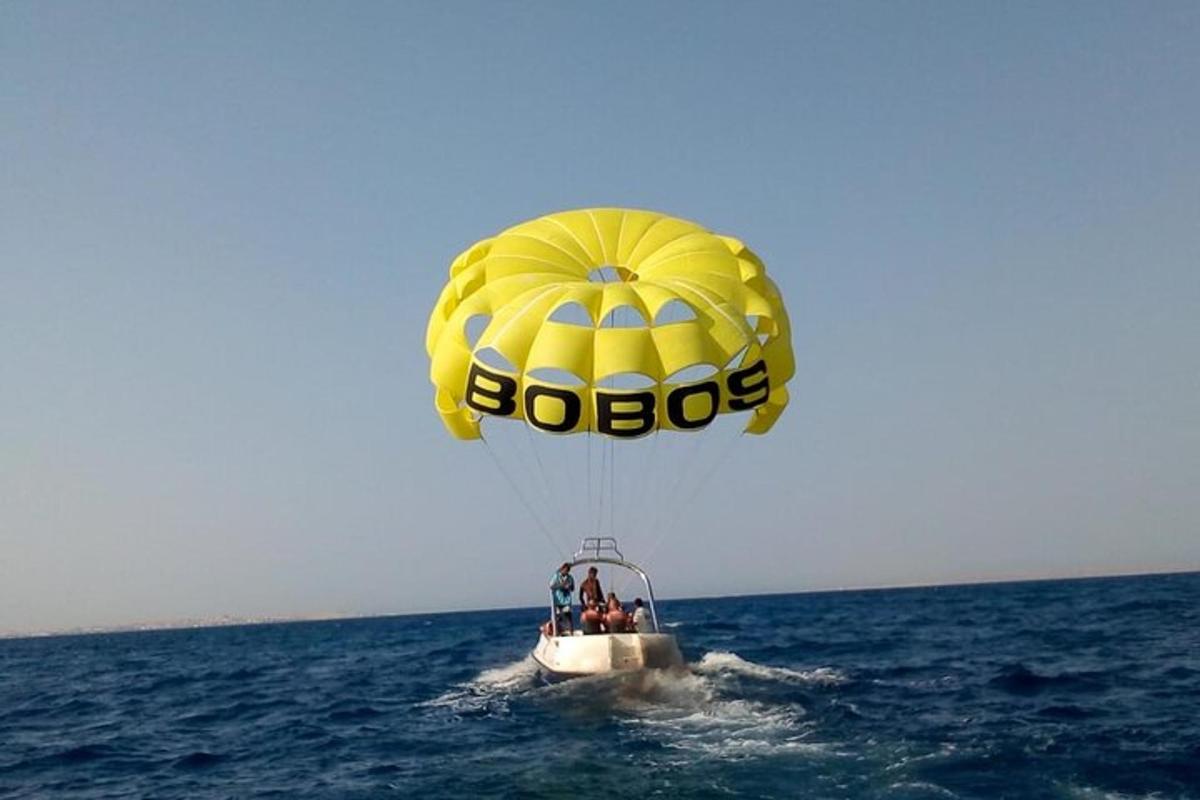 un paracadute giallo che vola sopra l'acqua con persone su una barca
