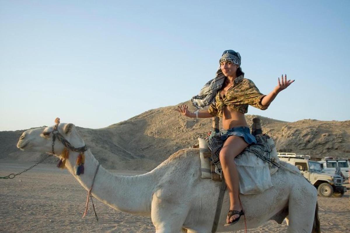 a woman riding on the back of a camel in the desert