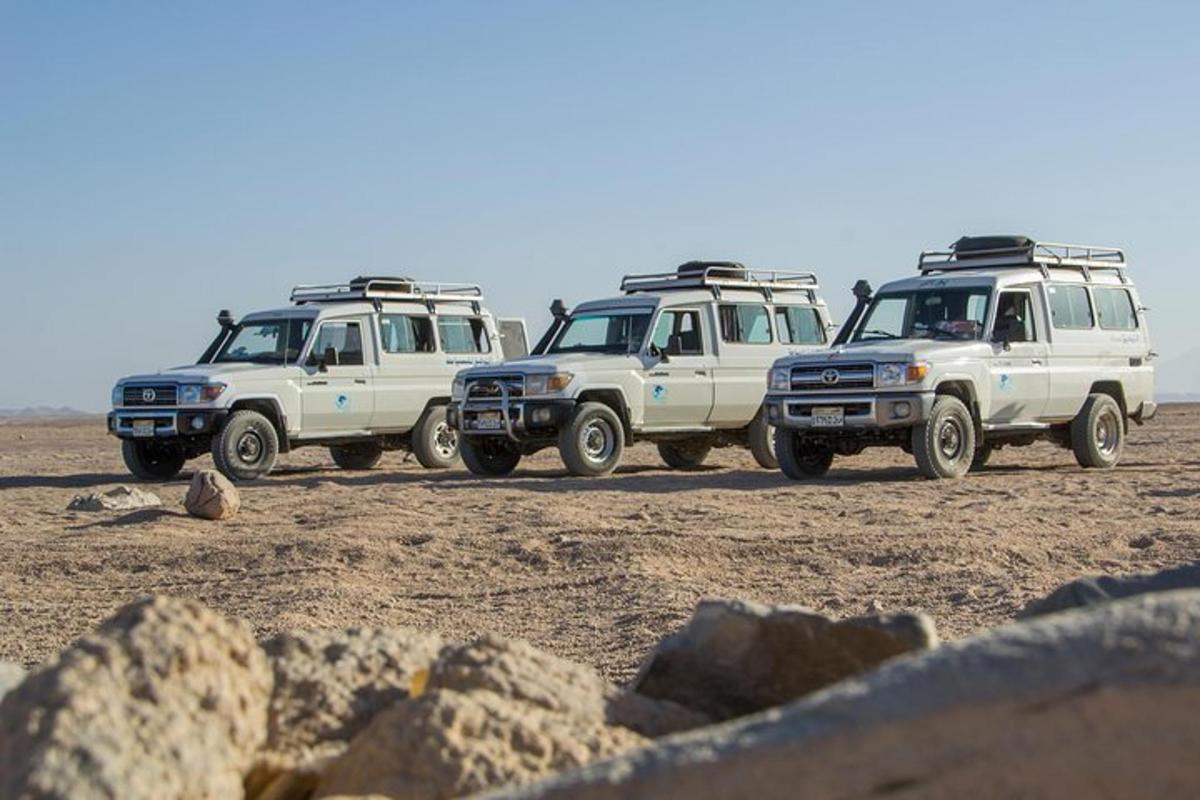 a group of three trucks parked in the desert