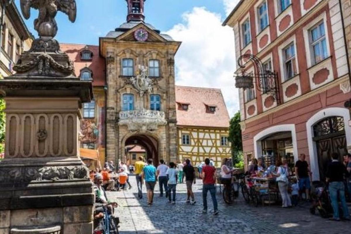 um grupo de pessoas caminhando por uma rua com uma torre do relógio