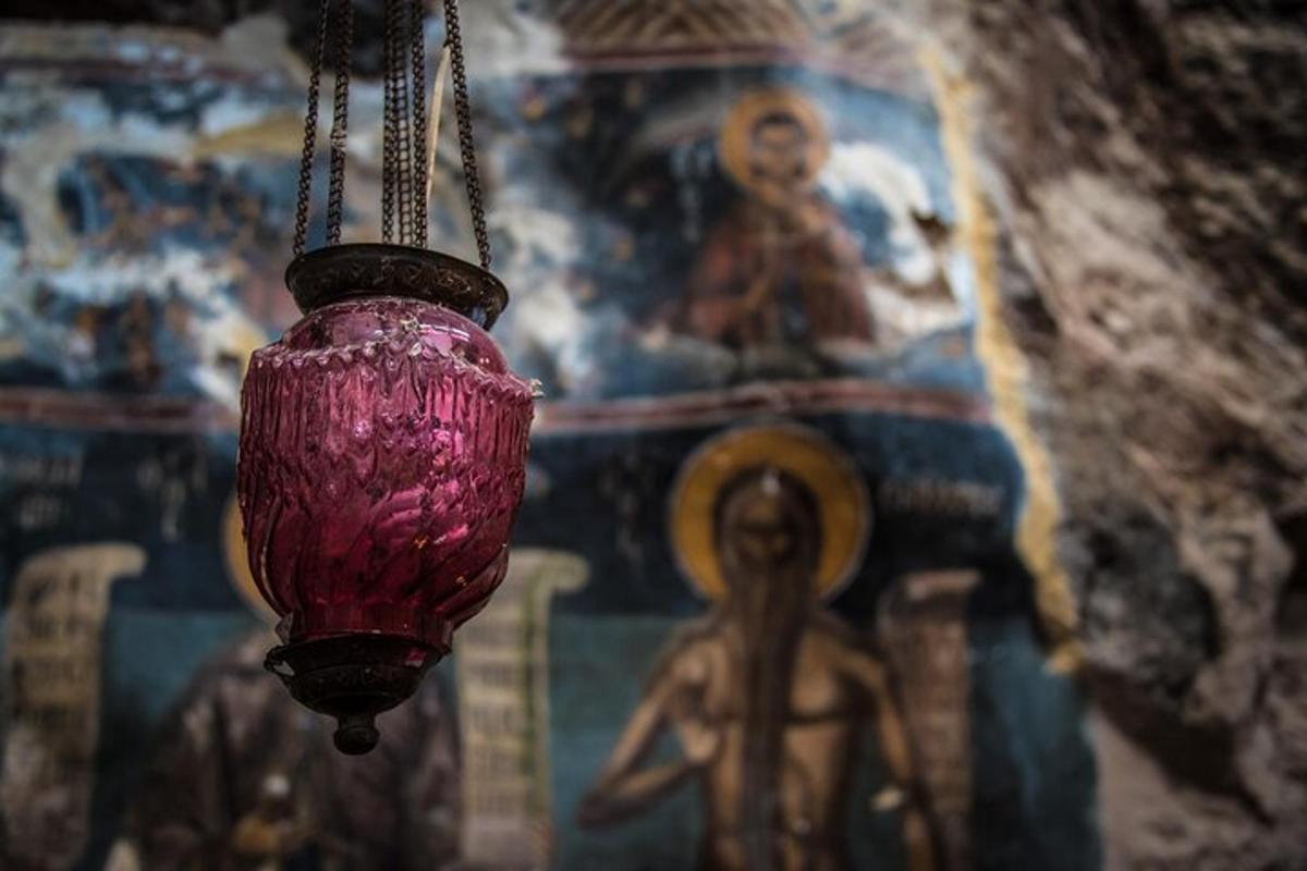 ένα ροζ φωτιστικό που κρέμεται από έναν τοίχο με μια τοιχογραφία