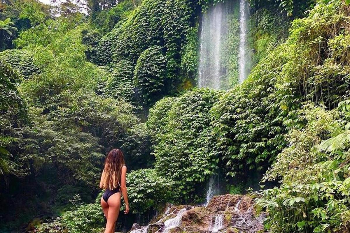 a woman standing on a rock in front of a waterfall