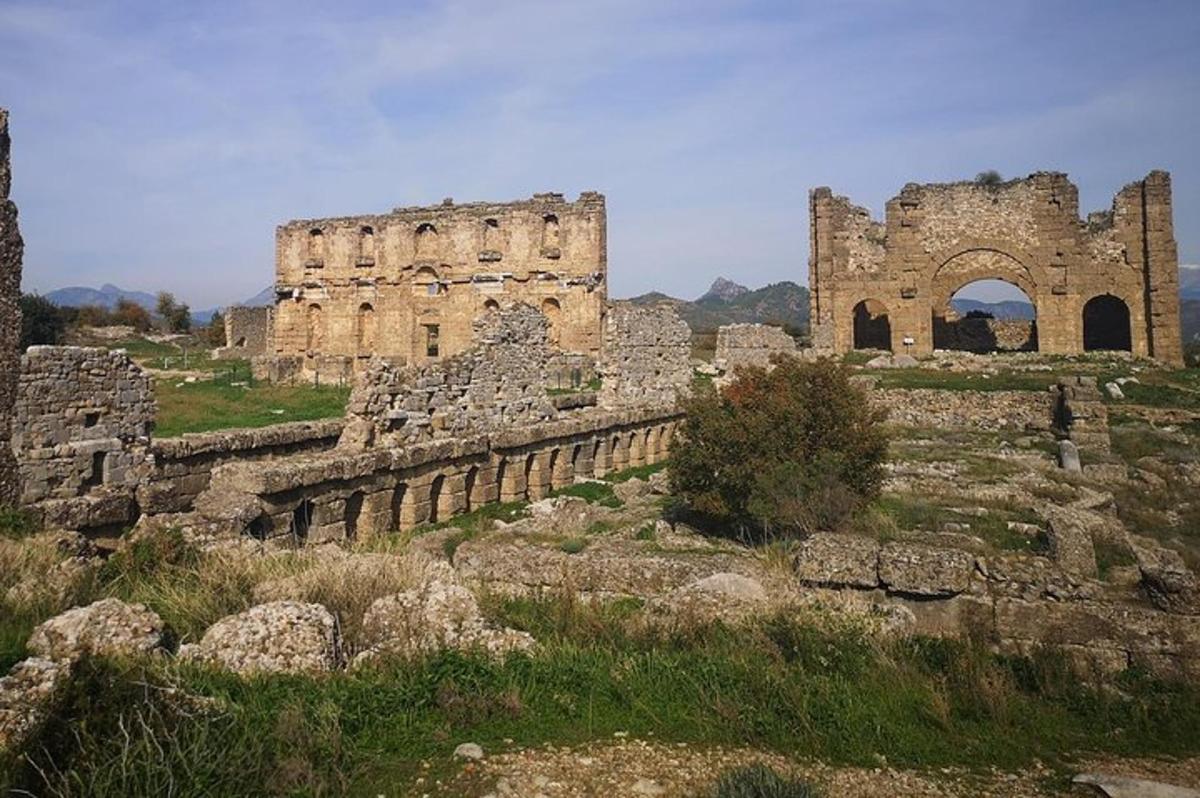 un vecchio edificio su una collina con erba e rocce