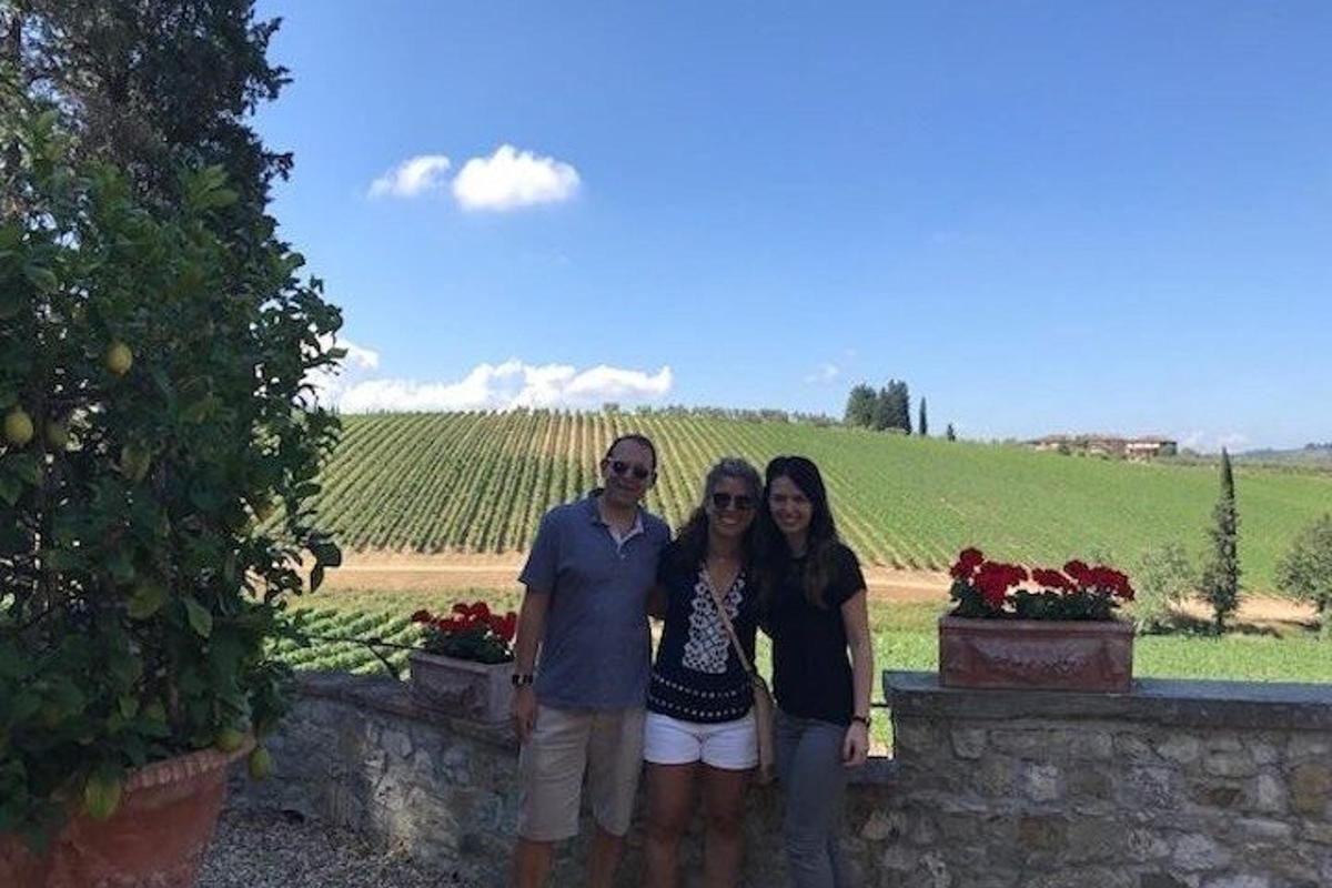 a group of three people standing in front of a vineyard