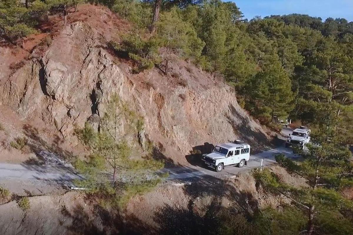 dwa pojazdy zaparkowane na drodze obok góry