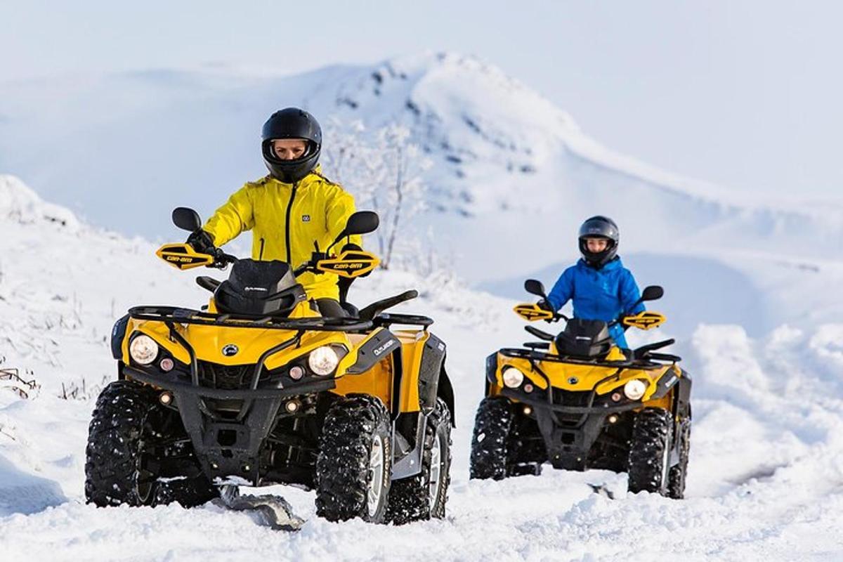 to personer kører på ATV'er i sneen