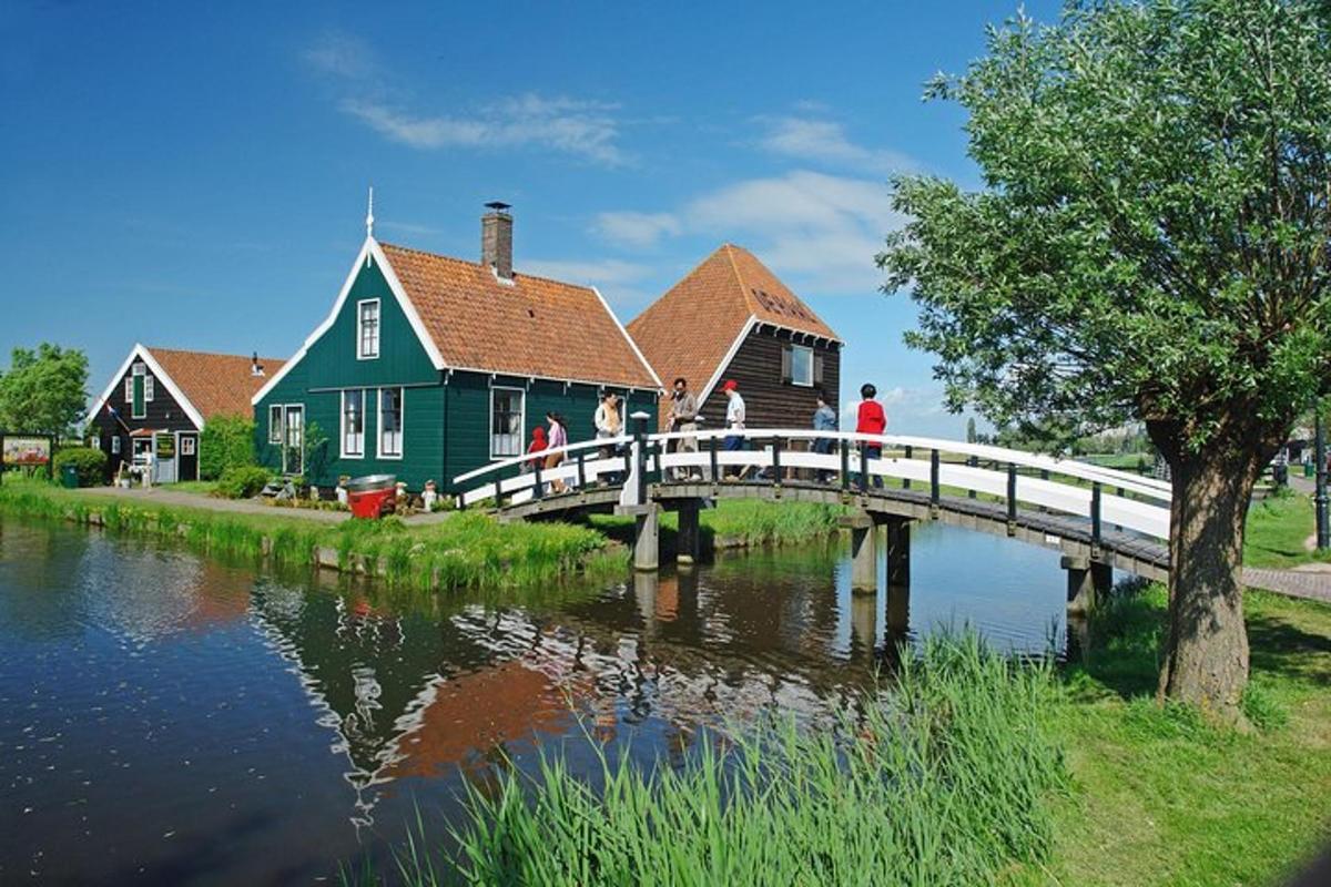 Menschen gehen über eine Brücke über einen Fluss mit einem Haus