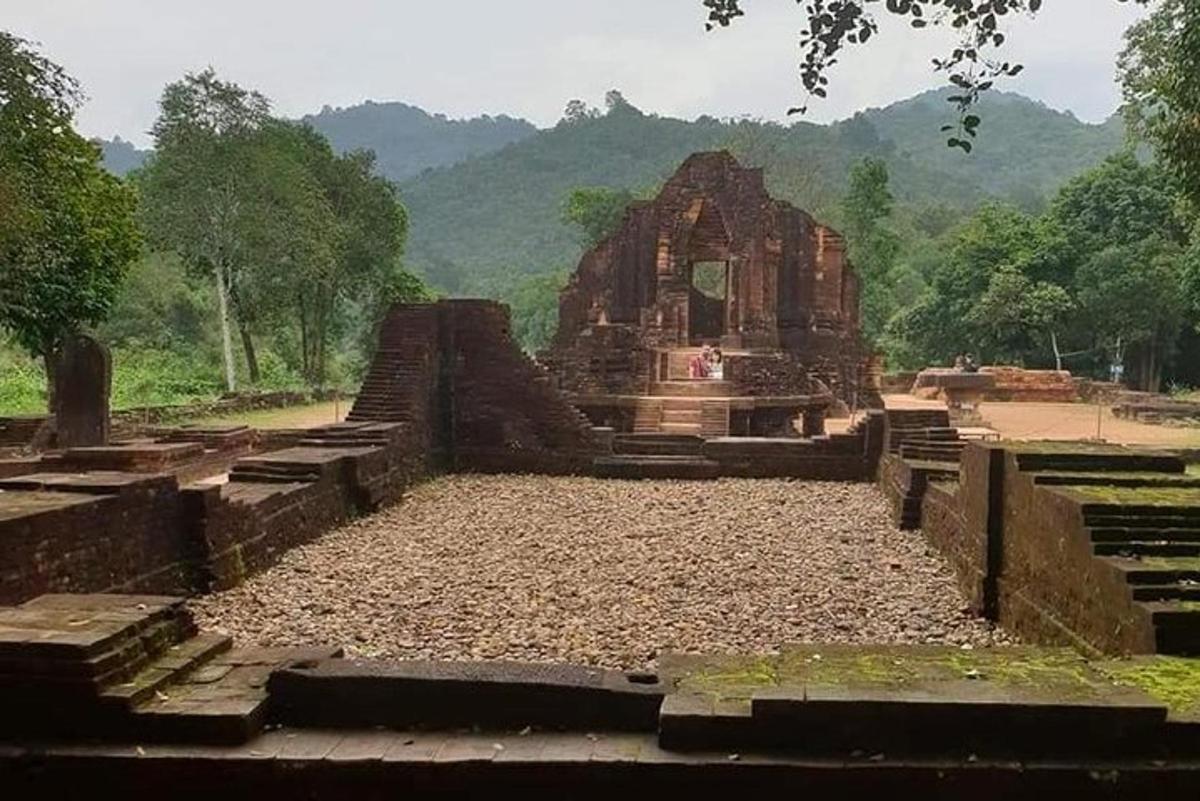 Un templo en un campo con montañas al fondo.