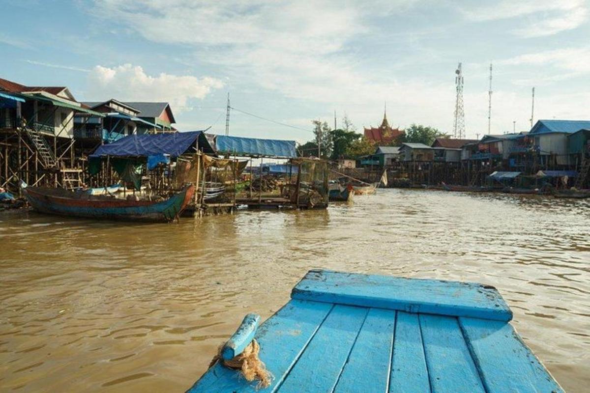 um barco azul em um rio com prédios e casas