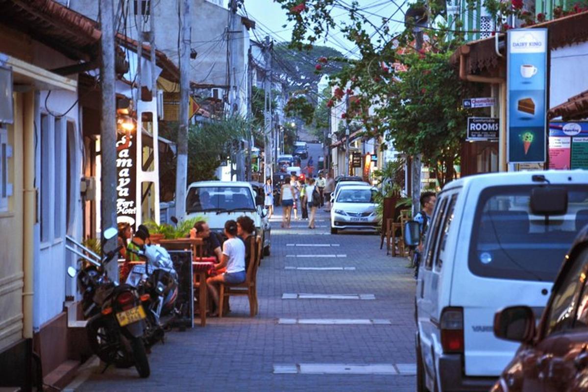 jalan bandar yang sibuk dengan kereta dan orang ramai duduk di meja