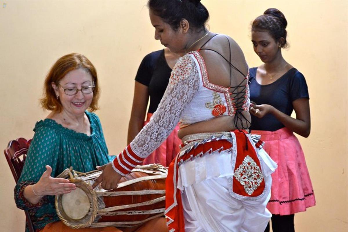 a woman playing a drum with three other women