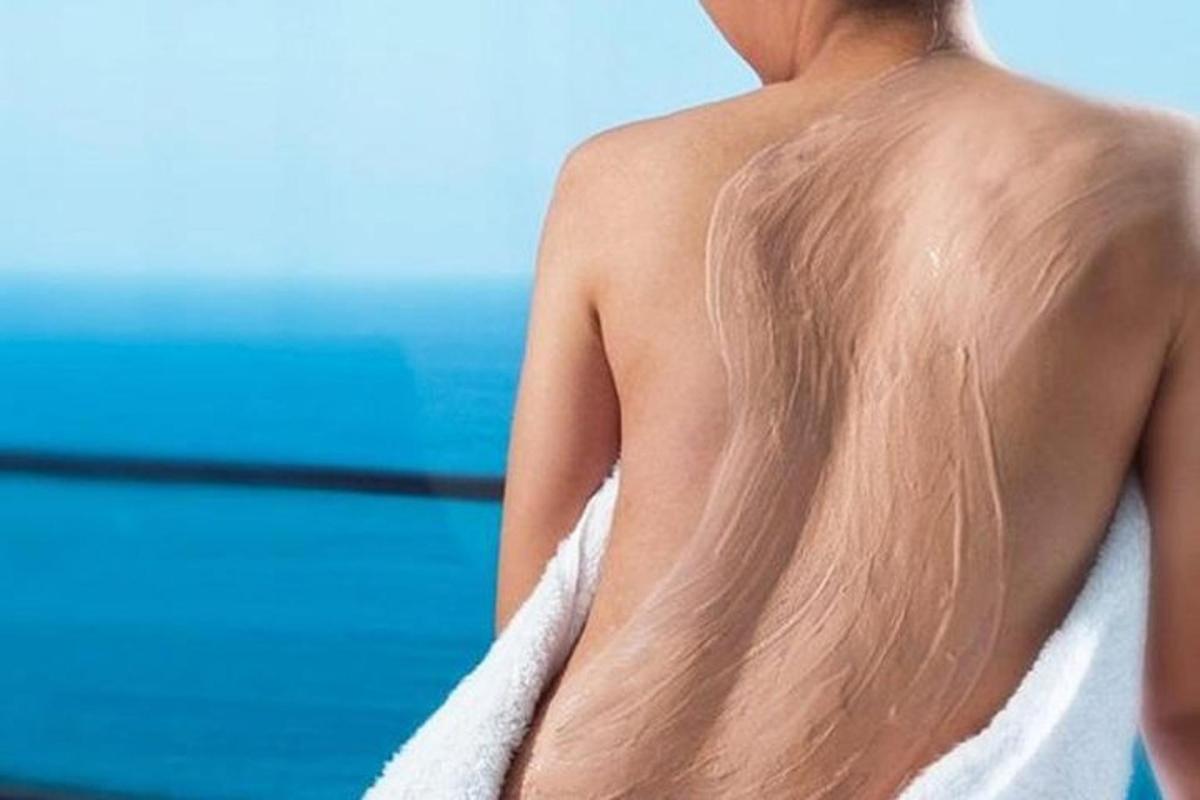 una donna con un asciugamano sulla schiena in spiaggia